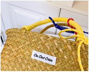 Detail of straw woven bucket bag with colorful nylon rope handle and brand label