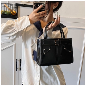Détail du sac à main en cuir verni noir avec boucle de ceinture et rivets métalliques