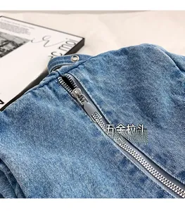 Detailed close-up of premium metal zipper on blue denim tote bag with textured fabric