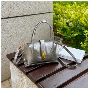 Silver transparent jelly bag with shiny inner pouch and gold clasp on a wooden bench