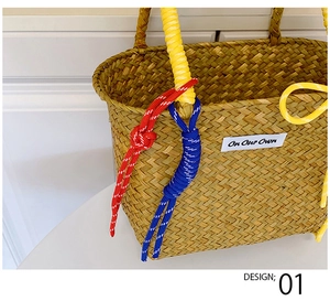 Detail of straw bucket bag featuring colorful decorative ropes and a brand text label