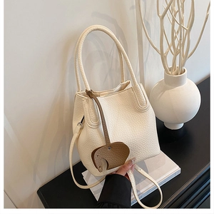 Détail d'un sac seau blanc texturé orné d'un charmant pendentif éléphant en cuir brun