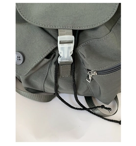 Detail view of nylon backpack with drawstring closure, buckle strap, and zipper pocket