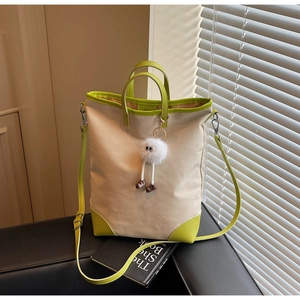 Detailed view of canvas tote bag with vibrant green trim and cute plush eye charm