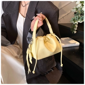 Detail of light yellow lychee grain leather handbag with drawstring pleats and metal hook