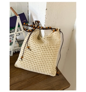 Gros plan du sac seau au crochet beige avec bandoulière en perles de bois