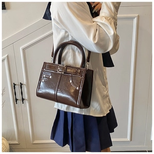 Détail d'un sac bandoulière en similicuir marron foncé avec surpiqûres et boucle