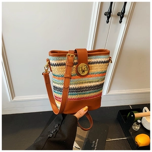 Close-up of colorful woven bucket bag with leather trim and gold metal twist lock