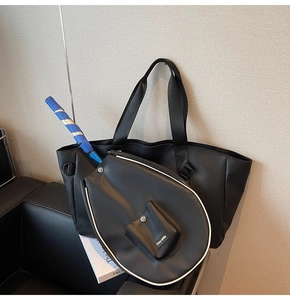 Close-up of black PU leather tennis tote bag with Grey-white racquet cover on leather sofa