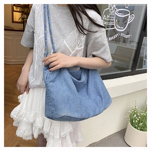 Detailed shot of washed blue denim tote bag featuring adjustable metal eyelet straps