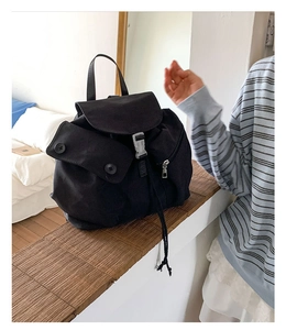 Detail of a black canvas backpack featuring secure buckles and convenient side zipper