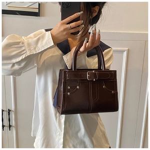 Détail d'un sac à main marron foncé brillant avec boucles et rivets rétro élégants