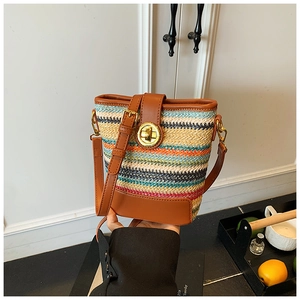 Detail of multi-color woven straw bucket bag with brown leather trim and golden twist lock