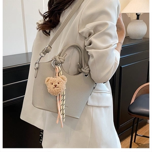 Light gray bucket bag with lychee texture featuring a cute brown plush bear charm