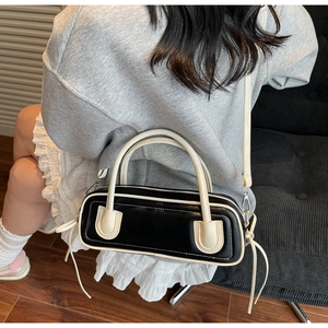 Macro shot of a black and white leather baguette bag worn with a casual outfit