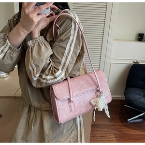 Pink pleated underarm bag with elegant pearl bow charm and glossy texture detail