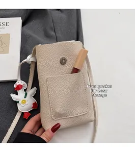 Detail of off-white lychee leather crossbody phone bag with front pocket and duck charm