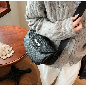 Detail of black quilted crossbody bag with textured fabric and stylish wide shoulder strap