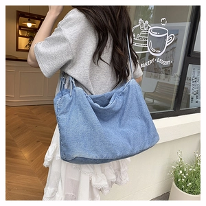 Detail of light blue denim hobo bag featuring a wide shoulder strap and spacious design