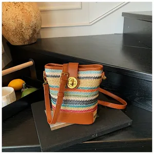 Macro detail of multi-color woven straw bucket bag with brown leather trim and gold hardware