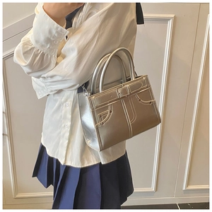 Détail du sac à main argenté métallisé avec poche style denim et boucle de ceinture