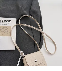 Detail of off-white lychee pattern leather phone bag with metal snap button and strap