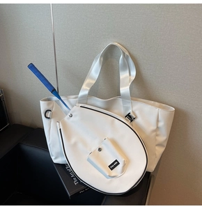 Close-up of a white sports tote bag with a racket slot on a stylish black sofa