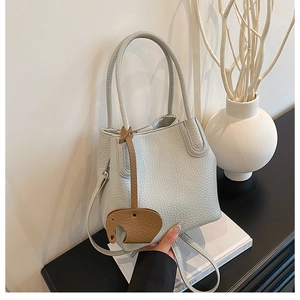 Vue détaillée du sac seau en cuir bleu clair avec charm éléphant marron sur la poignée