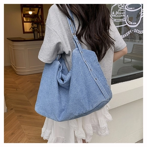 Detail of blue denim hobo bag with adjustable silver metal eyelet shoulder strap
