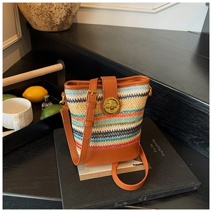 Detail of colorful woven bucket bag with brown leather trim and golden metal lock