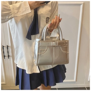 Détail d'un sac à main argenté métallisé avec motif poche en jean et poignée rigide