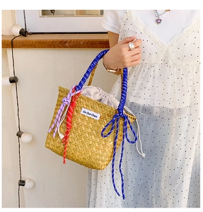 Detail of handmade straw bucket bag with blue rope handle and drawstring interior