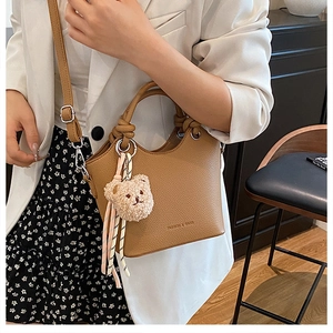 Brown lychee leather bucket bag with cute bear charm and adjustable shoulder strap detail