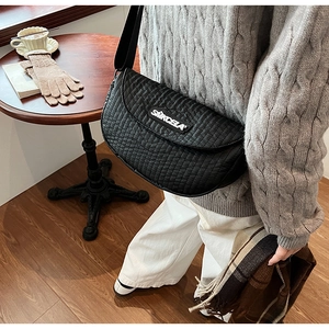 Close-up of black quilted saddle bag with adjustable wide strap and logo detail
