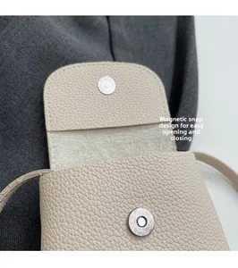 Detail showing the magnetic metal buckle and textured leather of the mini crossbody bag