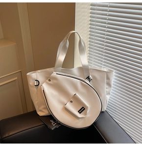 White large capacity tote bag and small matching pouch with brand logo on a black bench