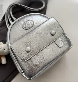 Detail of silver metallic mini backpack with crinkled texture and Fashion logo emblem