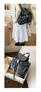 Detail of grey nylon backpack featuring drawstring closure and multiple utility pockets