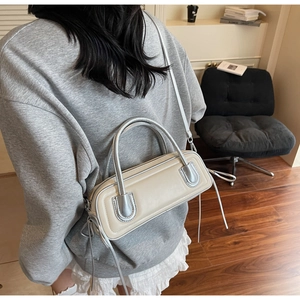 Detail view of cream leather cylinder bag with silver handles and zip closure