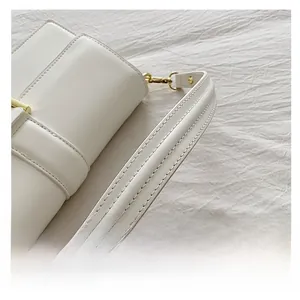 Détail de la bandoulière en cuir blanc avec boucle dorée et surpiqûres précises
