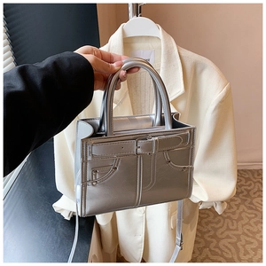 Détail d'un sac à main argenté métallisé avec design de poche en jean et sangle