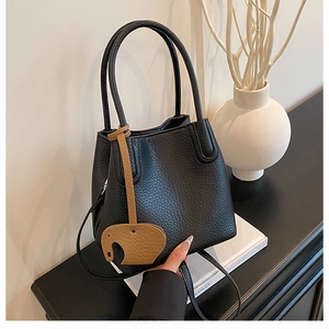 Détail d'un sac seau en cuir grainé noir avec un charmant pendentif éléphant marron