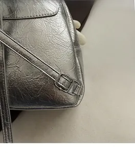 Detailed close-up of metallic silver leather texture and adjustable buckle hardware