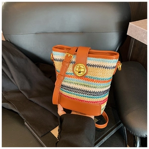 Close-up of colorful woven bucket bag with brown leather trim and golden metal lock