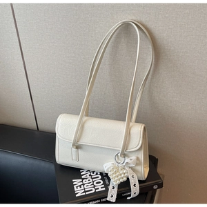 Detail of cream pleated faux leather shoulder bag with pearl heart charm and bow