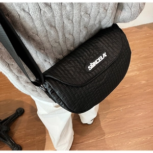 Detail of black quilted saddle bag with Simcela logo and wide nylon shoulder strap