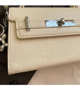 Detail of beige wrinkled texture handbag featuring silver twist lock and balloon dog charm
