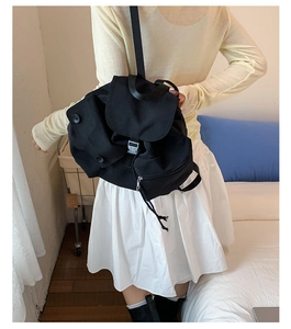 Rear view of a black casual canvas backpack with silver buckle on a female model