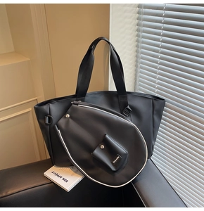Detail of minimalist black tennis bag and racket cover set on a stylish leather sofa