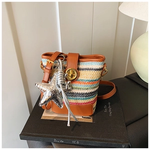 Detail of multi-color woven bucket bag with leather trim and shiny silver star charm